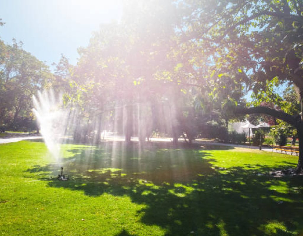 Newly installed sprinkler system watering green lawn evenly